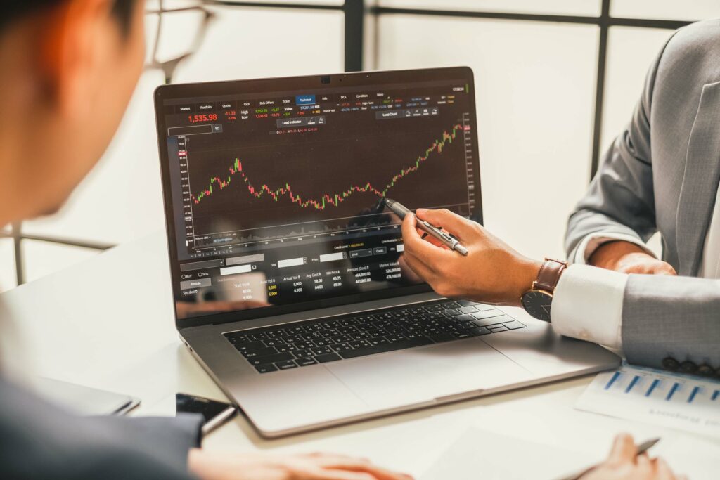 Businessman talking about investment stock market and graph from computer laptop with broker trader, giving money plan management and analysis. Depicts TradingView financial market chart.