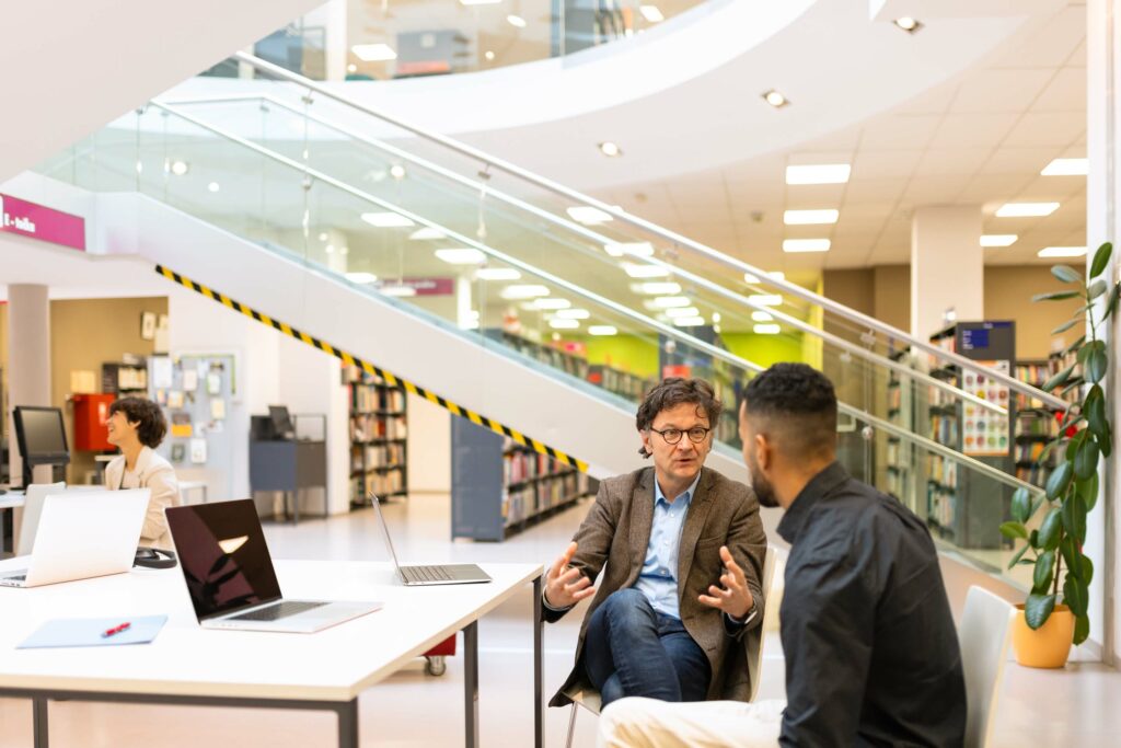 A group of adult visitors to the library learns and debates about the content read and learned. A racially mixed group of men and women use printed materials, books and notebooks, and phones in their learning. They examine the material of the university library and debate it.